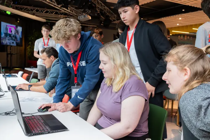 Students gathered around a laptop working on their game project