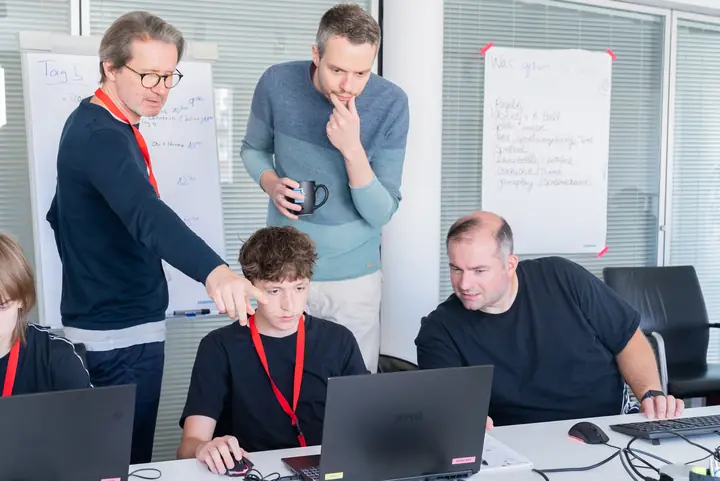Mentors helping a student at his laptop